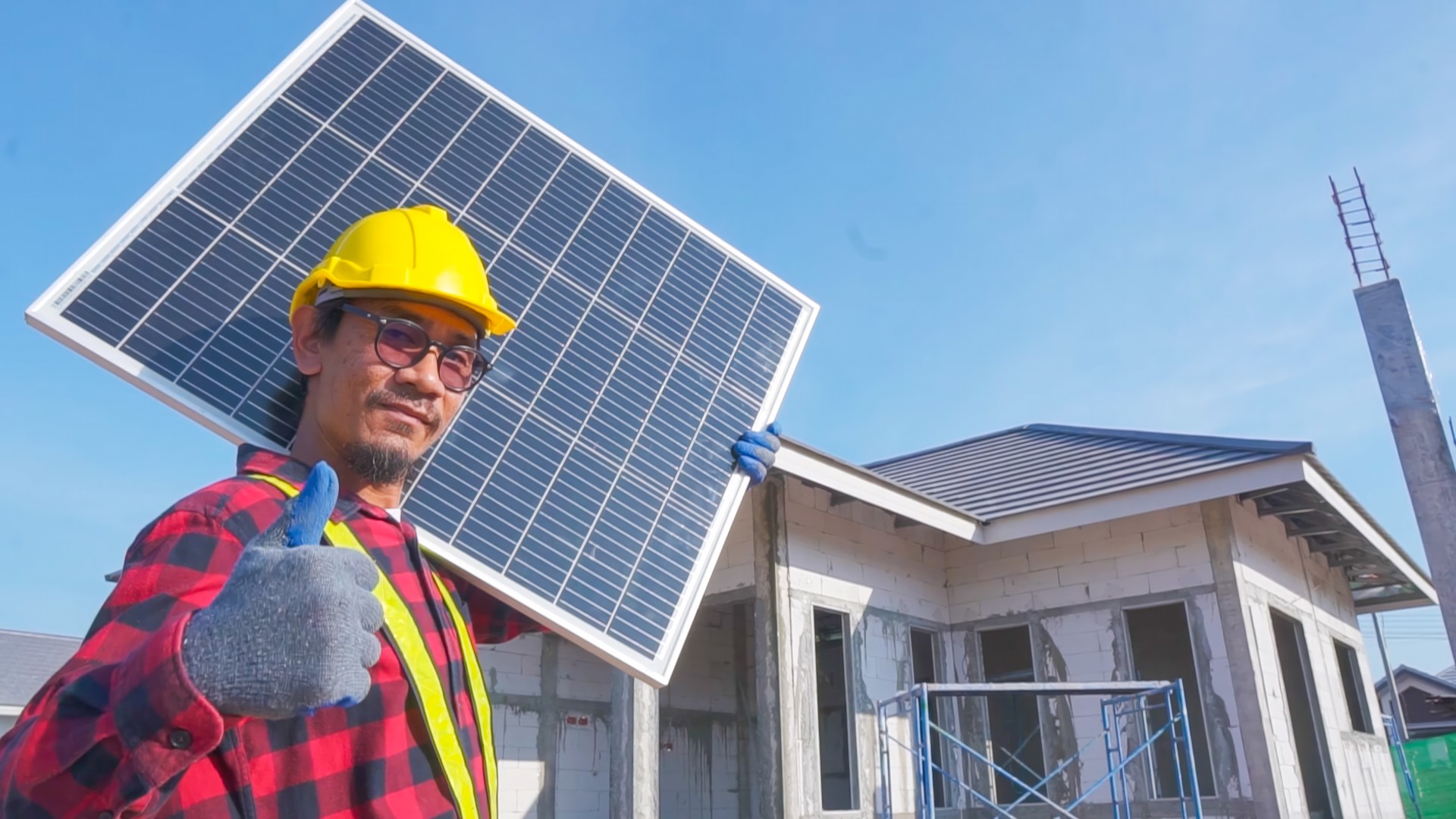 A worker installing solar panels. working on a construction site.Technicians installing solar panels on the roof of a house.